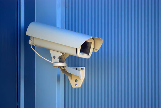 Das Bild zeigt eine Sicherheitskamera vor blauem Hintergrund.