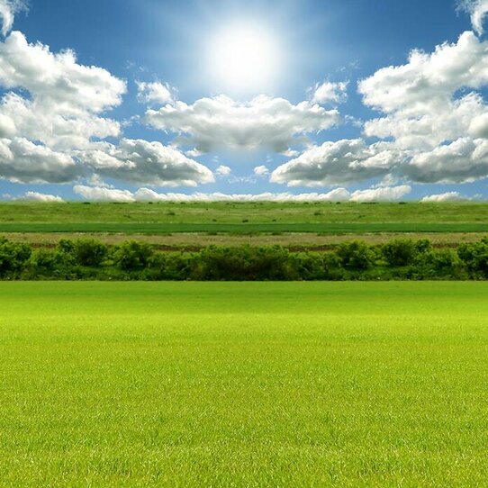 Landschaftsbild mit einer grünen Wiese Das Bild zeigt ein sonniges Landschaftsbild mit einer grünen Wiese und blauem Himmel mit einigen hellen Wolken.