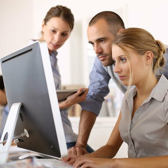 Drei Personen am Monitor Drei Personen, zwei Frauen und ein Mann, die sich gemeinsam etwas an einem Computer-Monitor ansehen.