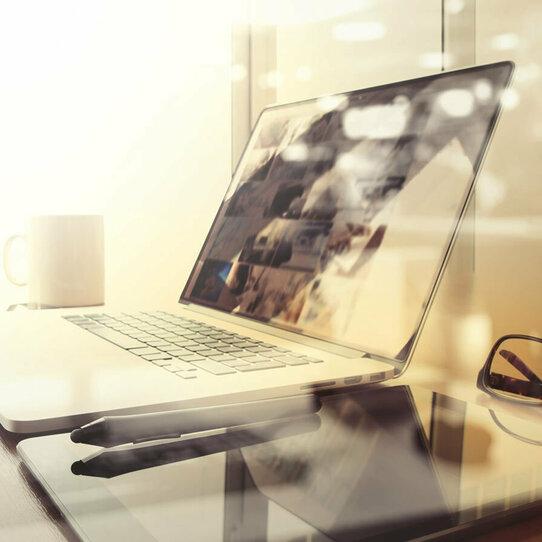 Büroarbeitsplatz mit Laptop Büroarbeitsplatz mit Laptop, Tablet Brille und Stift auf einem Schreibtisch mit unscharfem Hintergrund.