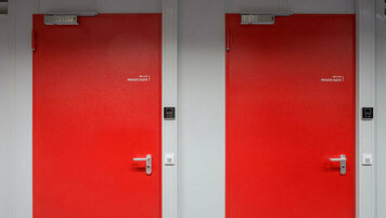 Auf dem Bild sind zwei rote Sicherheitstüren, die Zugang zu den KAMP Private-Suiten gewährleisten.