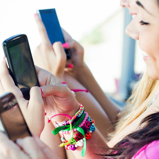 Mädchen an ihren Smartphones Das Bild zeigt drei fröhliche Mädchen mit ihren Smartphones.