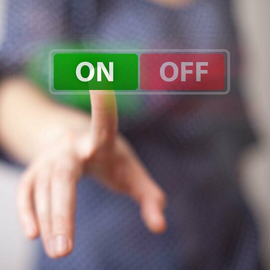 Hand, die einen "ON-Knopf" drückt, bei einer Auswahl zwischen "ON" und "OFF".