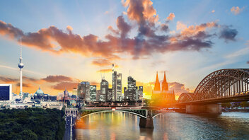 Skylines von Berlin, Frankfurt und Köln in einem Bild vor einem Sonnenuntergang.