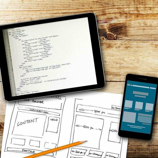 Tablet, Handy und Skizze auf Holzuntergrund Das Bild zeigt ein Tablet, ein Handy und eine Skizze auf einem Holzuntergrund.