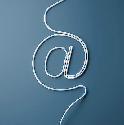 @-Zeichen @-Zeichen aus einem Kabel geformt vor blauem Hintergrund.